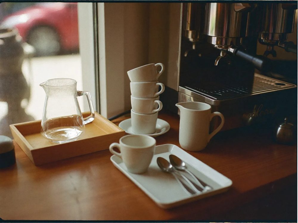 The serving counter with an espresso machine and a stack of white cups